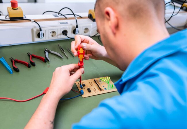 Auszubildender bei der Arbeit an einer Leiterplatte in der Lehrwerkstatt